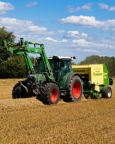 Grüner Ballenpresser auf einem geernteten Feld